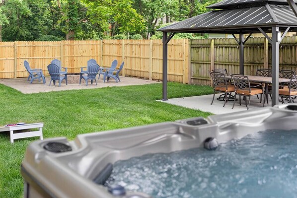 A backyard with a hot tub, a wooden deck, and outdoor furniture. - Olive & Brick | Hot Tub • Private Backyard Oasis (Cincinnati)