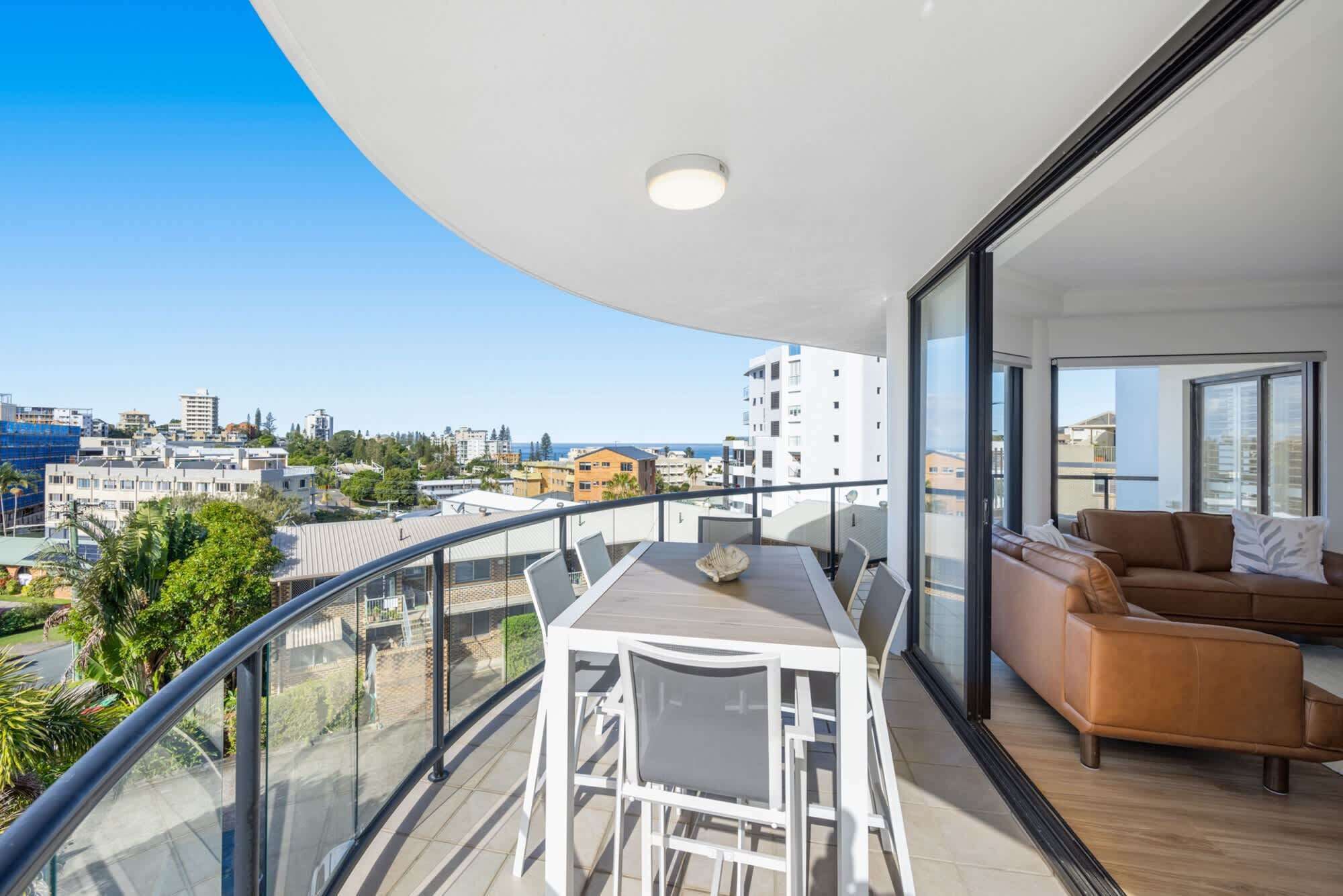 Varanda com mesa, cadeiras, um sofá e vista para a cidade.