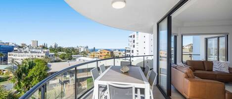 Varanda com mesa, cadeiras, um sofá e vista para a cidade.