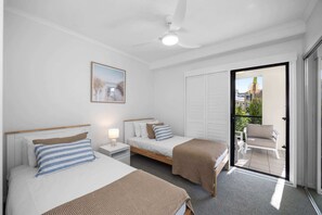 A hotel room with two beds, a ceiling fan, a nightstand with a lamp, a painting on the wall, and a sliding glass door leading to an outdoor seating area. - Poolside 3-Bed Retreat Near Kings Beach (Kings Beach)