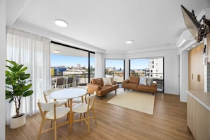 Eine moderne Wohnung mit Balkon, Essbereich und Wohnzimmer mit Sofa und Sesseln.