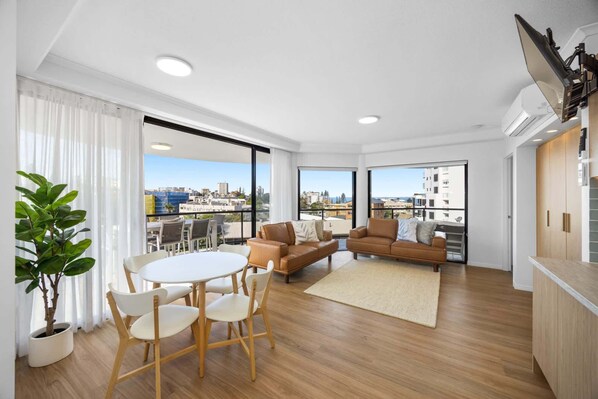 Un appartement moderne doté d’un balcon, d’un coin repas et d’un salon avec un canapé et des fauteuils.