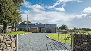 A stone building with a gravel driveway leading to a gated entrance. - Luxury Two Bedroom Holiday Cottage with Hot Tub and Sea Views | Y-Ddol (Dyffryn Ardudwy)
