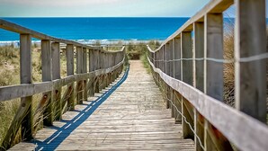 A wooden boardwalk leading to the ocean with a clear view of the sea and sky. - Luxury Two Bedroom Holiday Cottage with Hot Tub and Sea Views | Y-Ddol (Dyffryn Ardudwy)