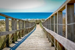 Una pasarela de madera que conduce al océano, con una vista despejada del mar y del cielo.