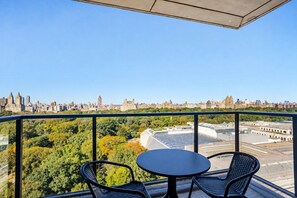A balcony with a table and chairs, overlooking a cityscape with buildings and trees. - Blueground | Upper East Side, fitness, nr MET (New York)