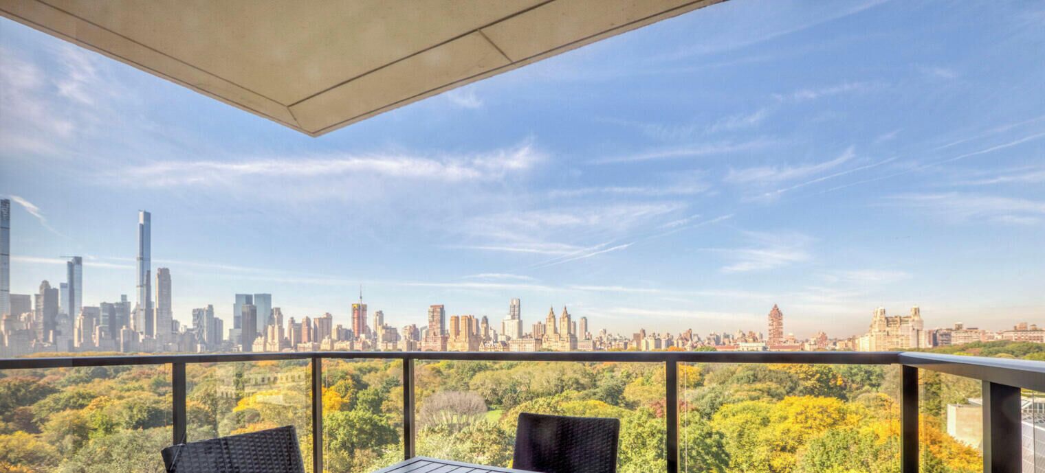 Un balcón con vistas a un horizonte urbano, una mesa y sillas.