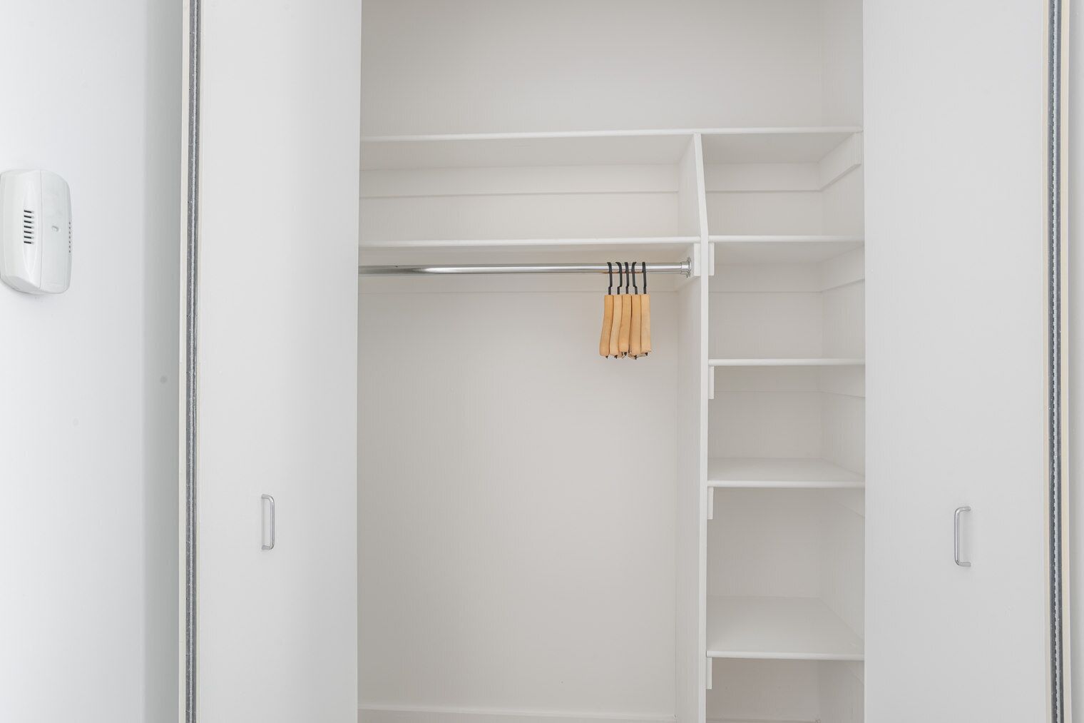 Un placard blanc avec plusieurs étagères et un espace pour suspendre les vêtements.