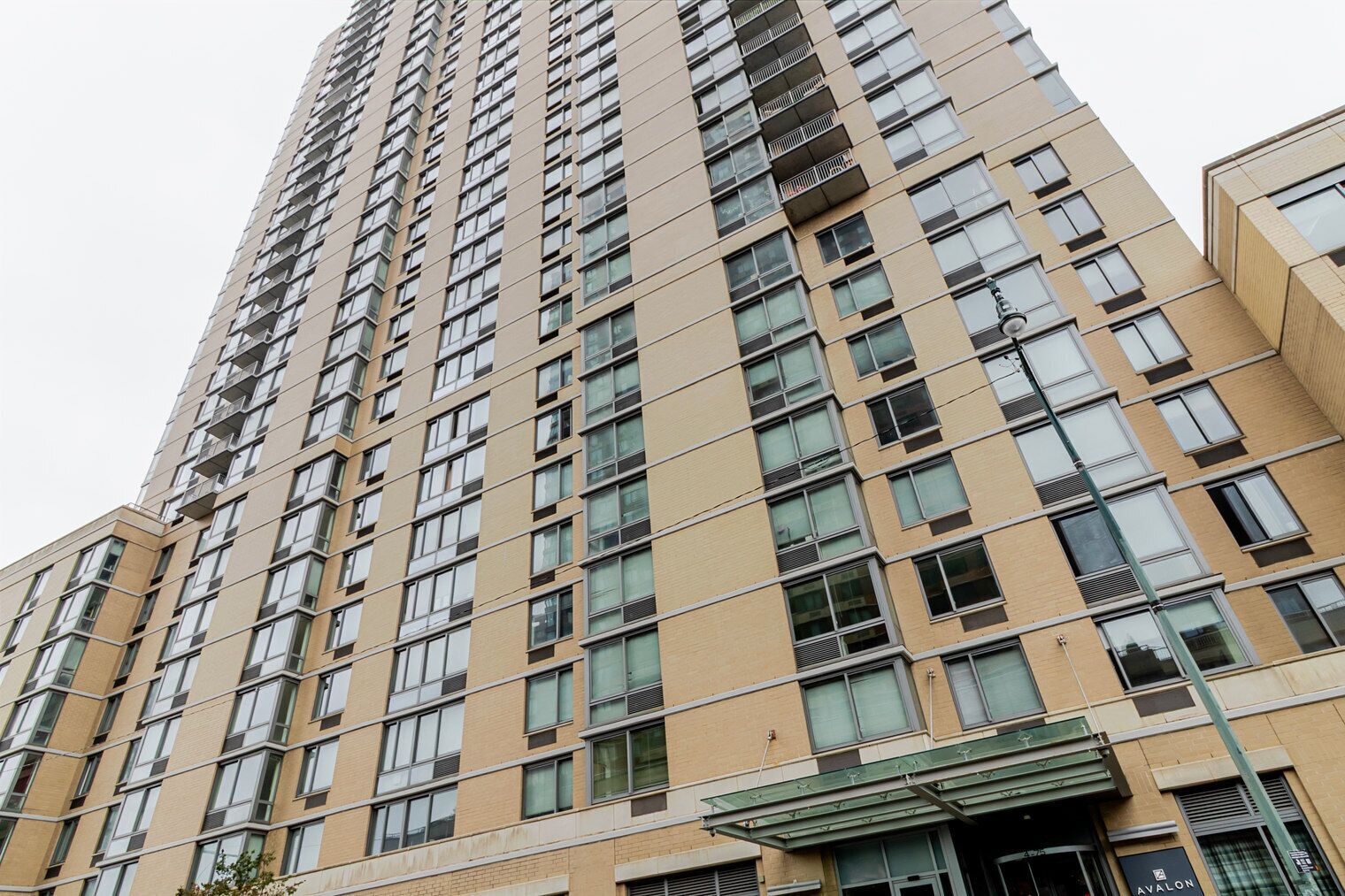A high-rise building with multiple floors, featuring a consistent window pattern and a central entrance with a glass canopy.