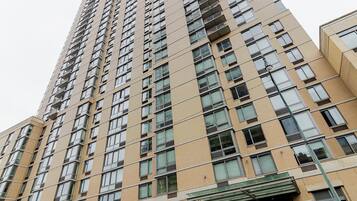 A high-rise building with multiple floors, featuring a consistent window pattern and a central entrance with a glass canopy.