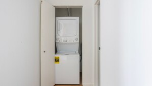 Uma lavanderia com máquina de lavar e secadora, etiqueta amarela de eficiência energética e piso de madeira.