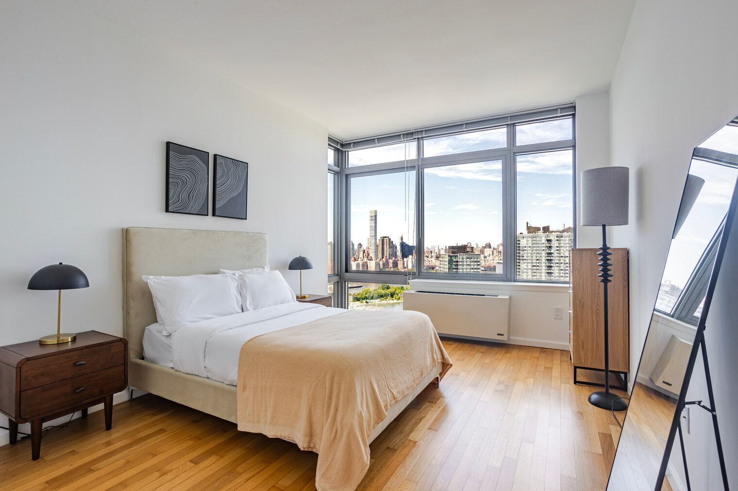 A modern bedroom with a large bed, a city view, and a skylight.