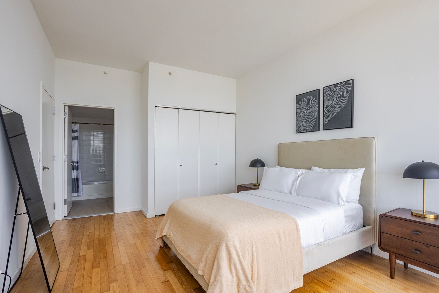 A bedroom with a bed, bedside tables, a wardrobe, and a mirror.