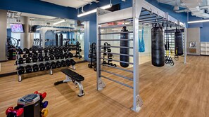 Ett gym med utrustning för styrketräning, en bänk och boxningssäckar.