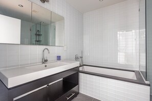 Ein modernes Badezimmer mit einem großen Spiegel, einem Waschbecken und einer Duschkabine.