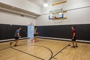 An indoor basketball court with a wooden floor, a basketball hoop, and padded walls. - Blueground | Hell's Kitchen, view, nr Times Square (New York)