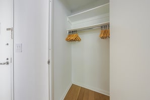 A white closet with a wooden floor, a hanging rod, and a door with a handle and lock. - Blueground | Manhattan, rooftop, nr Battery Park (New York)