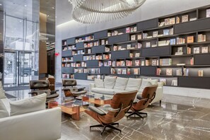 Eine moderne Bibliothek mit Bücherregalen, Ledersesseln und einem Glastisch.