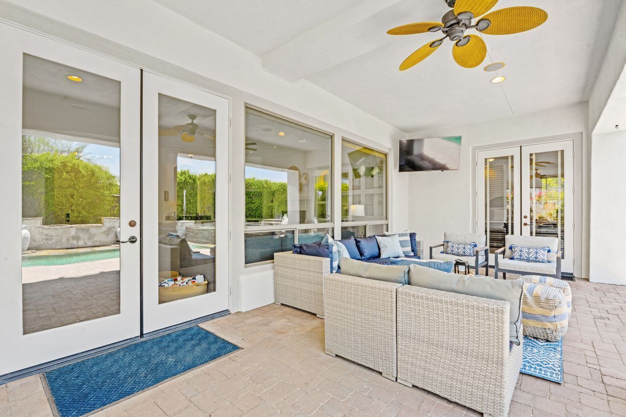 An indoor patio area with a wicker sofa, chairs, and a ceiling fan.