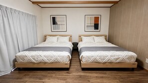 A double bed room with a wooden floor, two bedside tables, and two framed abstract paintings on the wall. - Iki-ju, Hanazono-cho · Accommodates up to 10 people · 1 free parking space · 6-minute walk from Hanazono-cho Subway Station · 5 minutes to Shinsaibashi, Namba, and Nihonbashi (大阪市)
