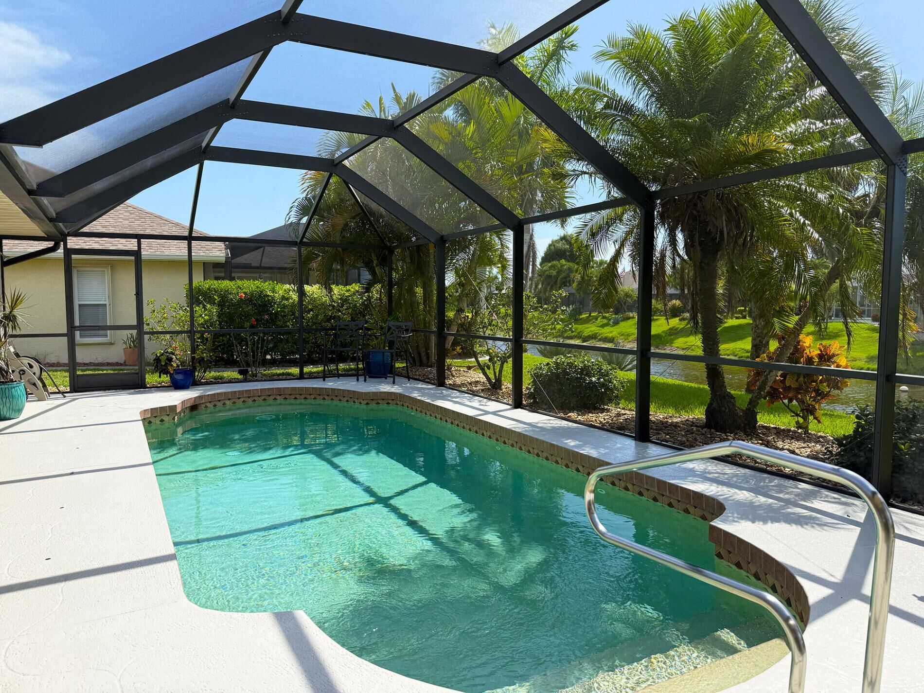Une piscine dotée d’un espace couvert, entourée de verdure et d’une maison.