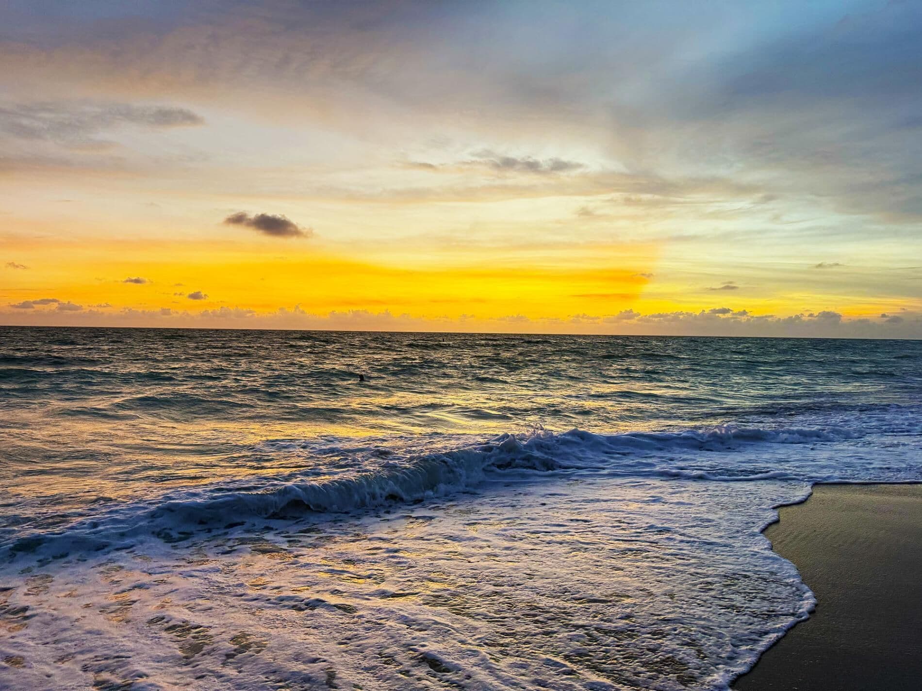 Une plage avec des vagues et un coucher de soleil.