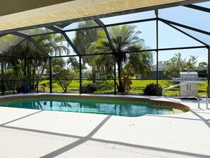 A pool area with a covered patio, clear pool water, and surrounding greenery. - 3BR Heated Pool Villa - Golf & Beaches (Rotonda West)