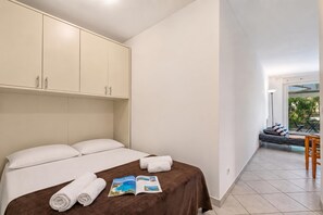 Ein Hotelzimmer mit einem Bett, einer Zeitschrift und Blick auf den Außenbereich mit Sitzgelegenheiten.