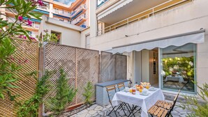 A patio with a table set for breakfast, surrounded by a wooden fence and greenery. - Appartement Les Jasmins, Beaulieu sur Mer, France (Beaulieu sur Mer)