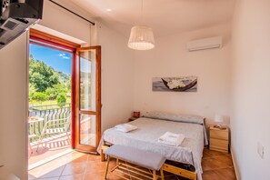 Ein Schlafzimmer mit Bett, einer Bank, einem Tisch, einer Hängelampe und einem Bild.