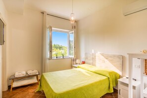 Ein Schlafzimmer mit Bett, Fenster, Nachttisch und Lampe.