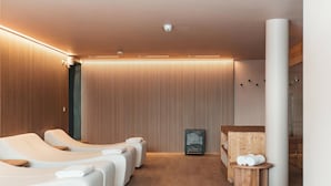 Un moderno spa con sillones de masaje, pared de madera y zona de ducha con mampara de vidrio.