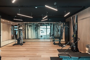 A modern gym with various exercise equipment, including treadmills and weight machines, and a large mirror wall. - Residenza Castanea 001 Modern Alpine Stay In San Bernardino | Ski, Hiking & Nature, San Bernardino, Switzerland (San Bernardino)