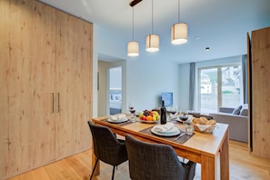 A modern dining area with a wooden table, chairs, and a view of the city through large windows. - Residenza Castanea 001 Modern Alpine Stay In San Bernardino | Ski, Hiking & Nature, San Bernardino, Switzerland (San Bernardino)