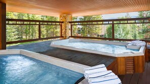 A hot tub area with a wooden deck, a stone pillar, and a view of trees. - 2-Bedroom Condo @ HGVC Valdoro Mountain Lodge, Breckenridge, CO - Christmas Week (Breckenridge)