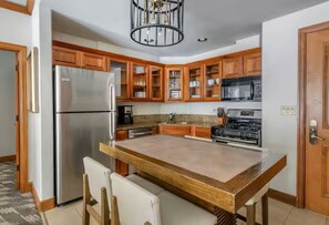 Eine Küche mit Holzausstattung, einem Edelstahl-Kühlschrank, einer Mikrowelle und einem Herd.