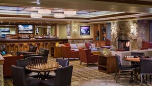 Eine Hotelhalle mit Barbereich, Sitzgelegenheiten, einem Kamin und einem Fernsehbildschirm.