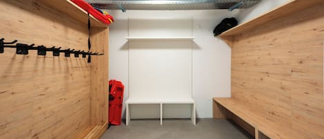 A narrow, enclosed space with wooden walls, a white bench, and a red object on the floor.