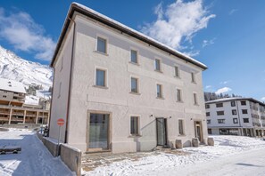 Un edifici de diversos pisos amb terra coberta de neu, un senyal de prohibició d'entrada i un cel serè.
