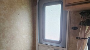 A compact interior with a window, a small sink, and a blue mat on the floor. - Camper 6 Enjoyable 2-bedroom recreational vehicle with AC just out of Fair Play. (Fair Play)