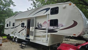 A recreational vehicle with a slide-out camper section, a small enclosed area, and a window. - Camper 6 Enjoyable 2-bedroom recreational vehicle with AC just out of Fair Play. (Fair Play)