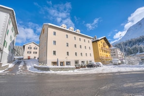 Un hotel de varios pisos con un patio central, rodeado de calles nevadas y montañas.