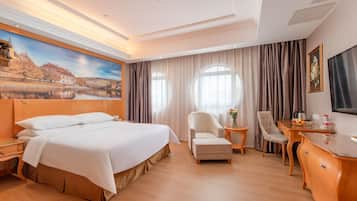 Una habitación de hotel con una cama grande, dos sillas, una mesita y un escritorio.