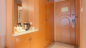 A hotel room with a wooden wardrobe, a minibar with tea and coffee, and a door with a keycard reader. - Vienna Guangzhou Beijing Rd Gongyuanqian (Guangzhou)