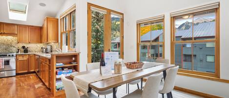 A modern kitchen with wooden cabinets, a granite countertop, and a dining area with a table and chairs.