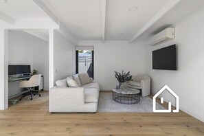 Ein modernes Wohnzimmer mit Sofa, Couchtisch und Fernseher.