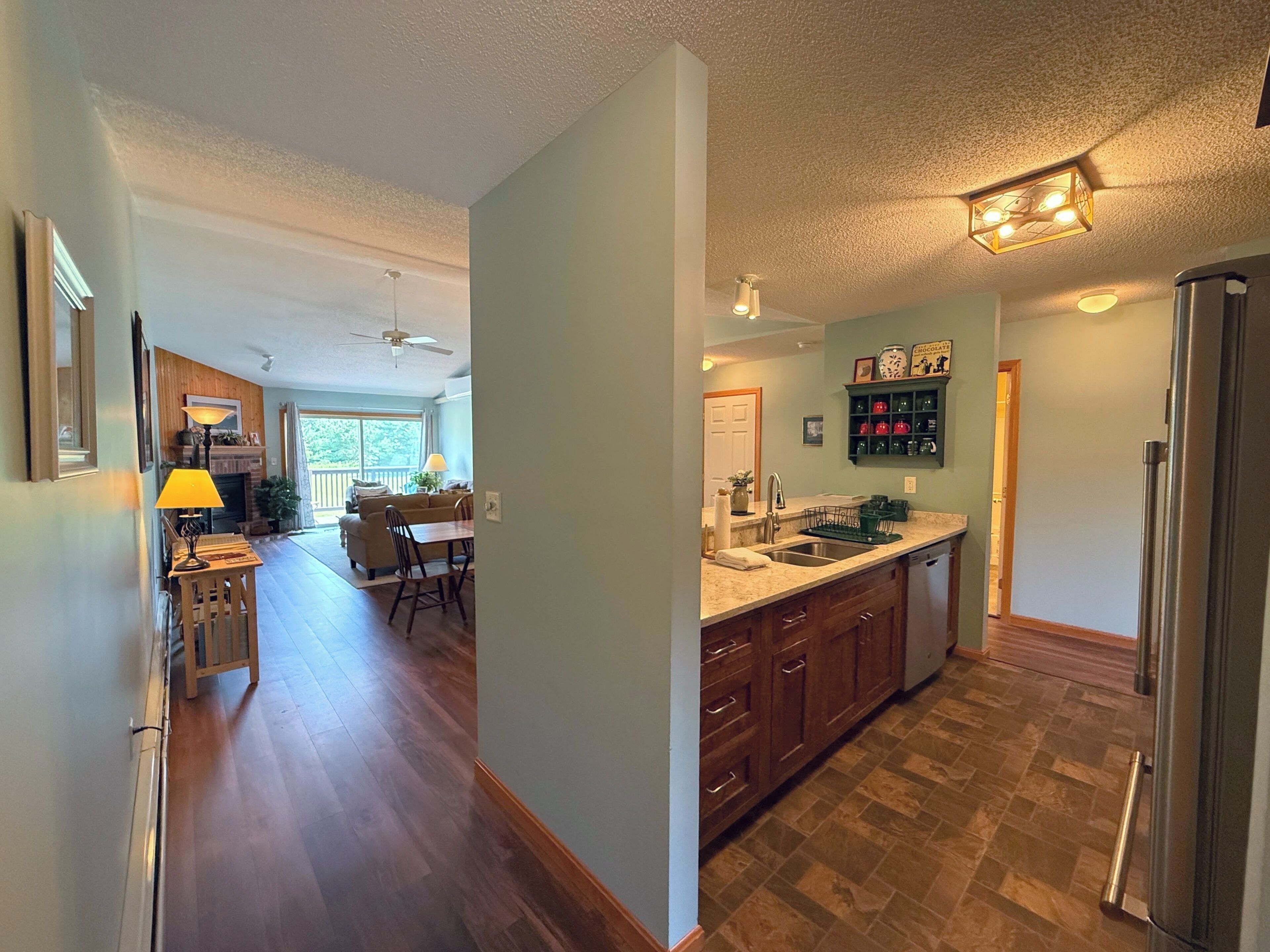 A kitchen with wooden cabinets, a stainless steel refrigerator, and a dining area with a table and chairs.