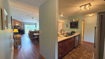 A kitchen with wooden cabinets, a stainless steel refrigerator, and a dining area with a table and chairs.