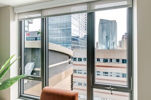 Ein Zimmer mit großem Fenster und Blick auf moderne Gebäude sowie ein geschwungenes architektonisches Element.