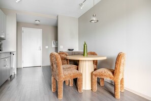 Une cuisine moderne avec une table de salle à manger ronde, quatre chaises en osier et un luminaire suspendu.